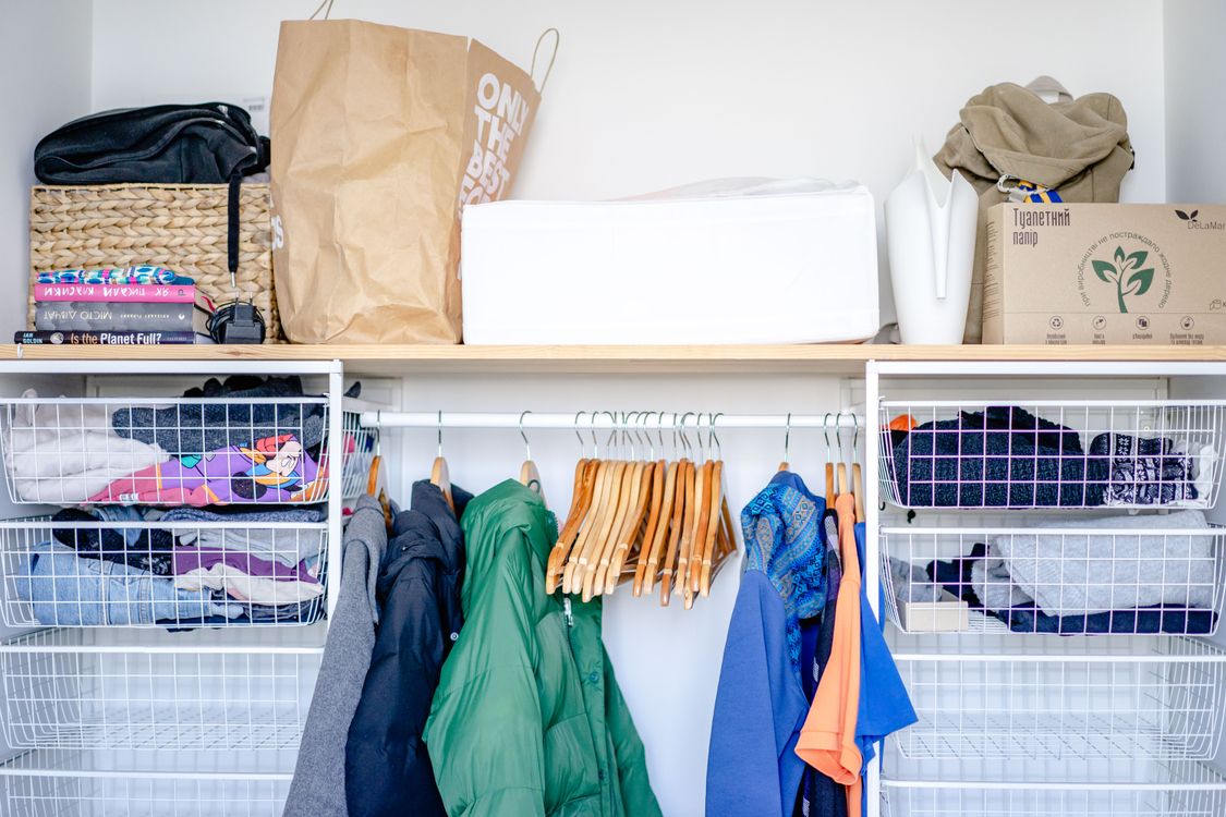 Garde-robe organisée avec vêtements sur cintres et paniers de rangement